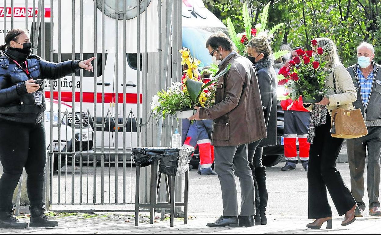 Varias personas reciben la indicación de aplicarse gel hidroalcohólico a la entrada del cementerio.