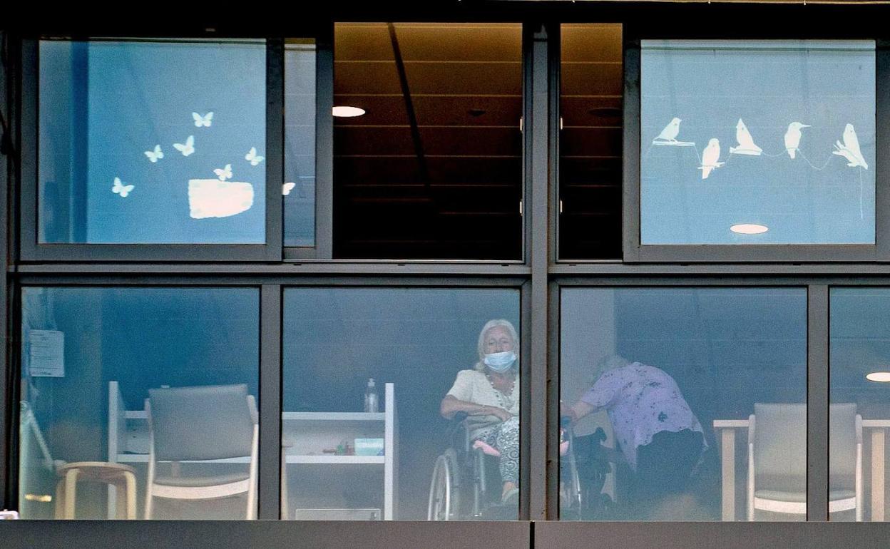 Una mujer mira por la ventana de una residencia de Cataluña.