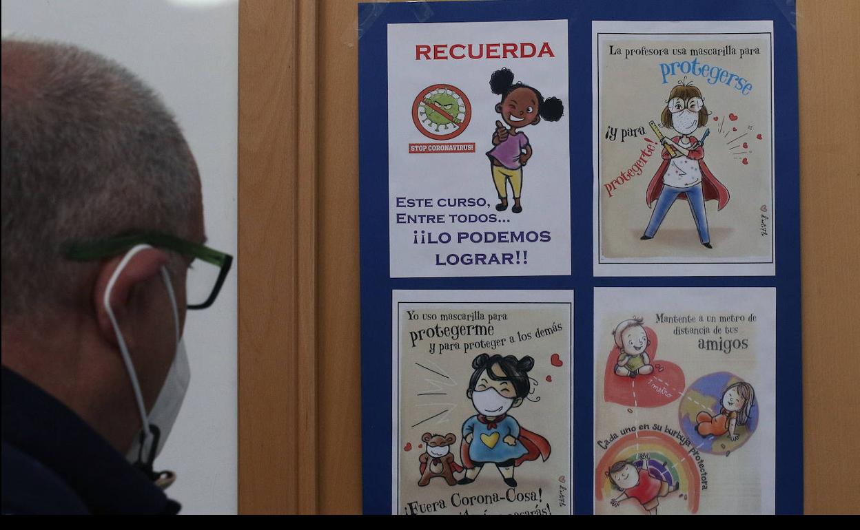 Un hombre observa un cartel sobre la covid en un colegio de Segovia. 