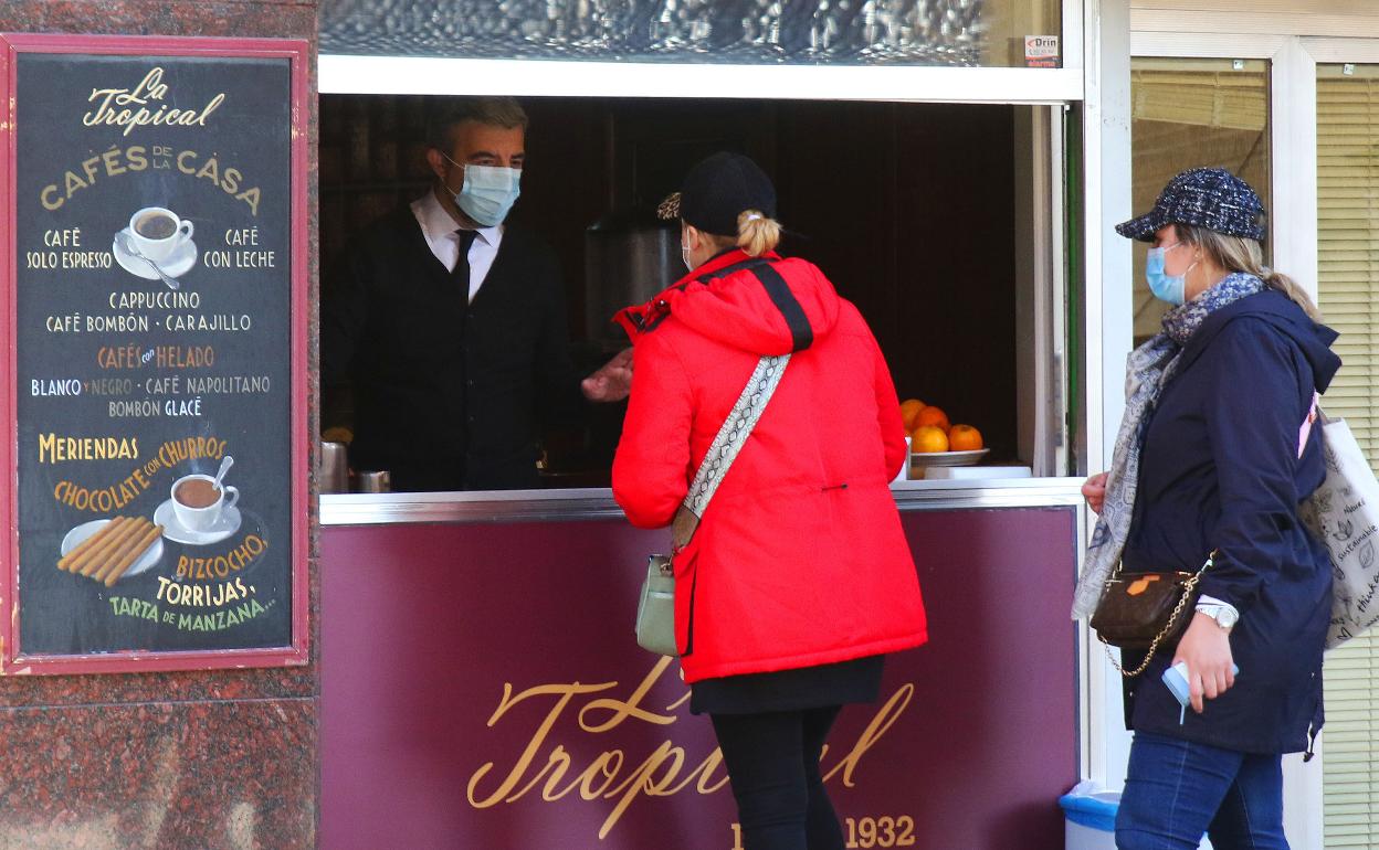 Un camarero atiende pedidos a través de la ventanilla del bar..