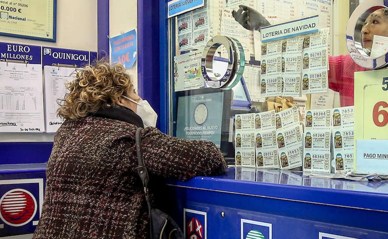 Una señora compra lotería en una administración. 