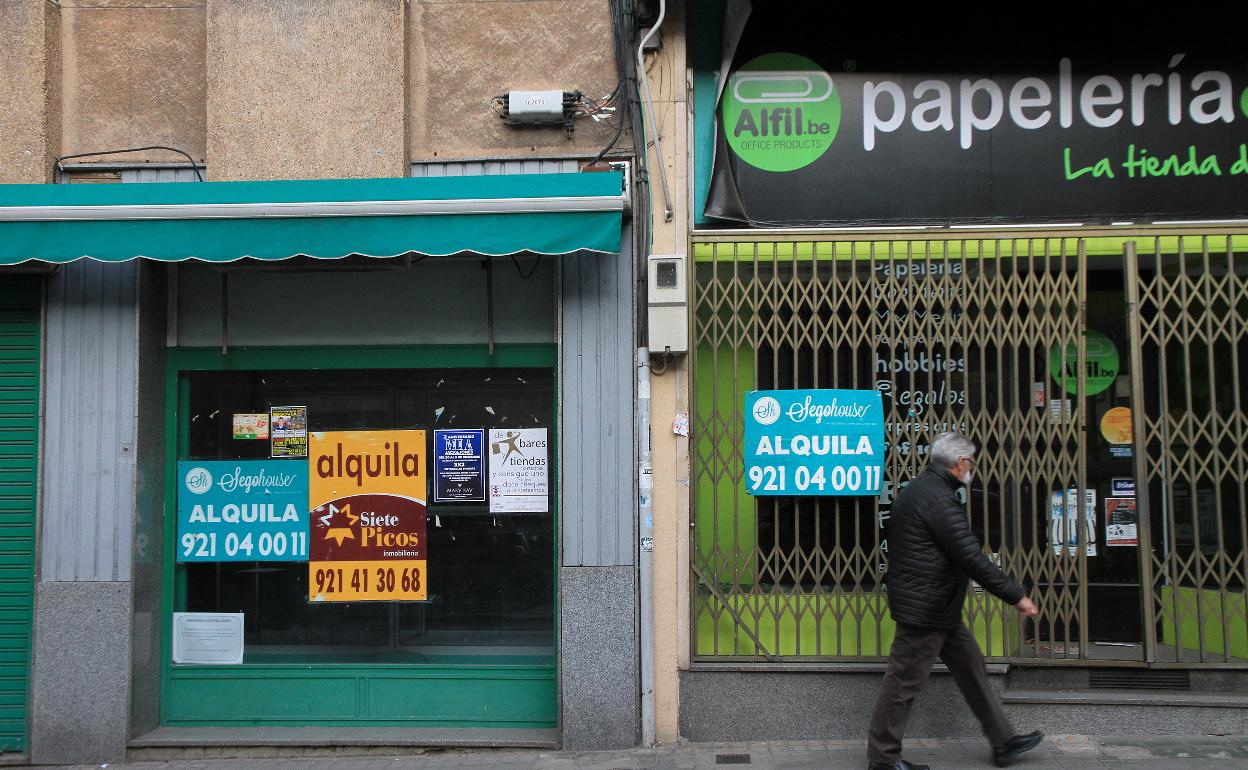 Un hombre camina junto a locales cerrados.