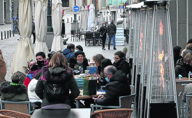 Algunos clientes sentados alrededor de las estufas en una terraza de un bar de Segovia, ayer. 