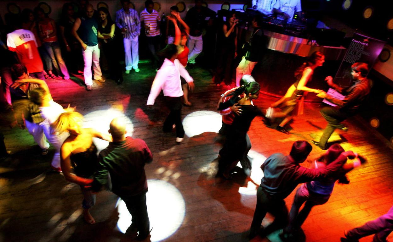 Varias parejas bailan en una discoteca.