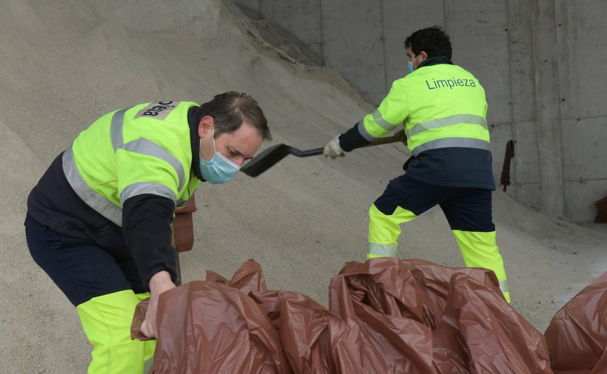 Los operarios preparan los sacos de sal para el temporal de las próximas horas. 