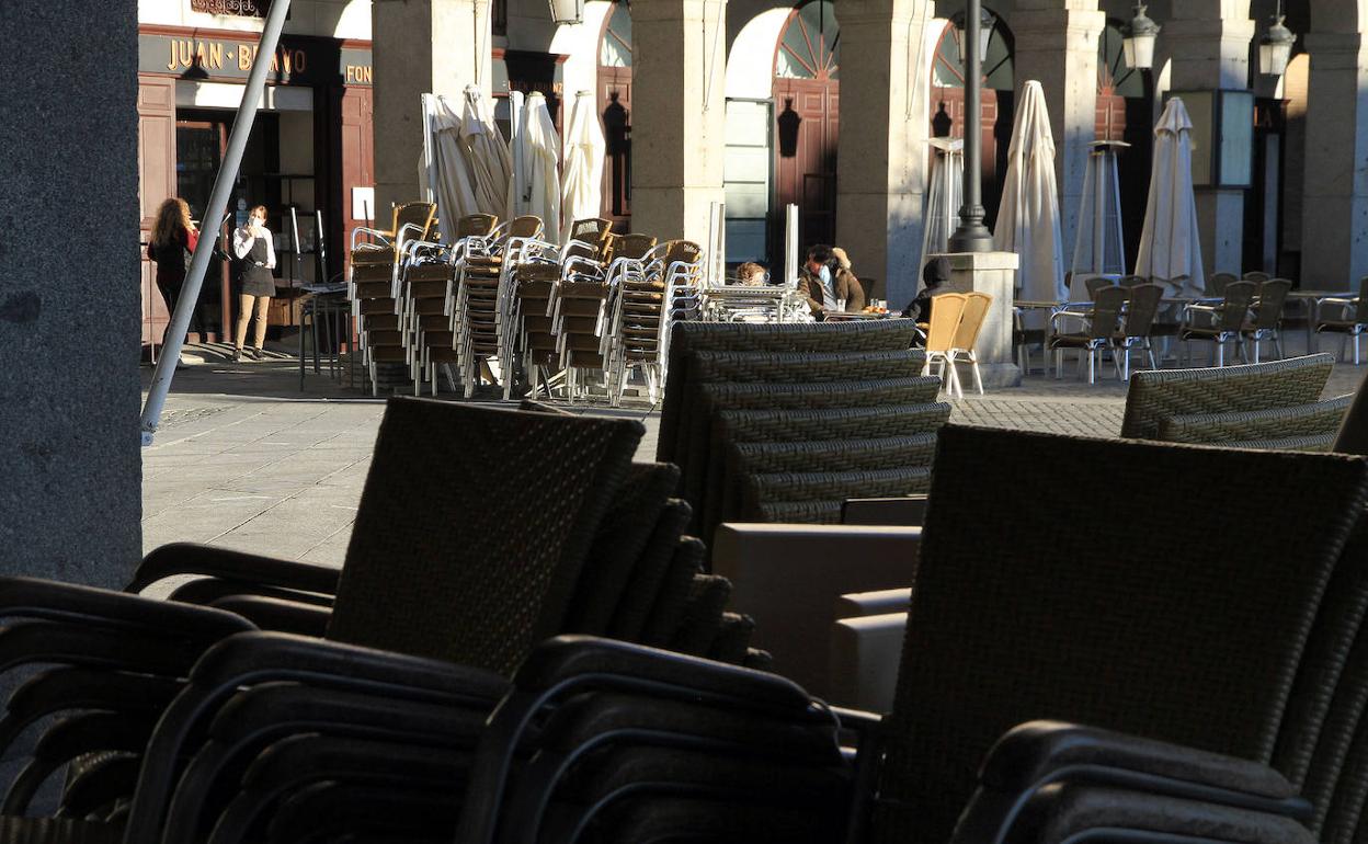 Pilas de sillas y mesas de terrazas recogidas en la Plaza Mayor de Segovia. 