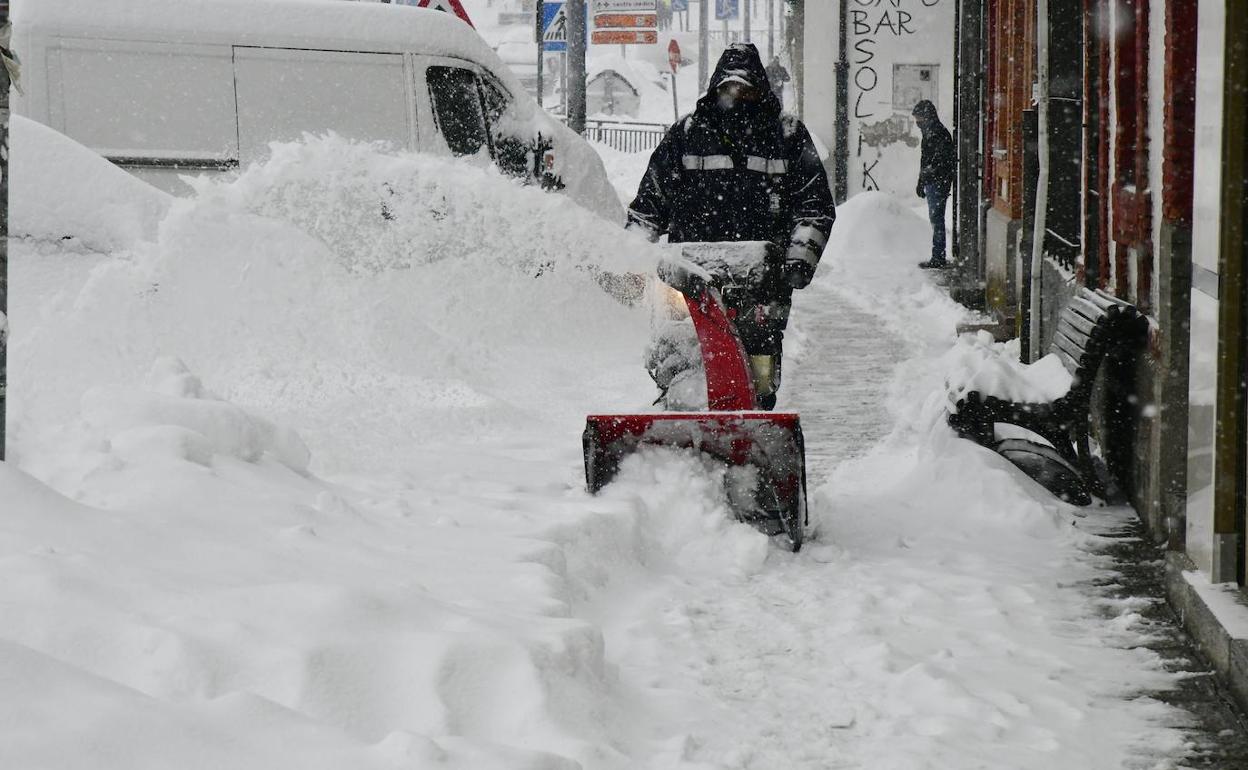 Un vecino despeja la nieve acumulada en una acera en San Rafael, El Espinar. 