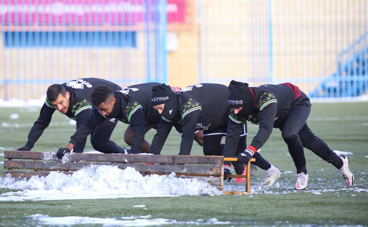 Los jugadores del CD Guijuelo ayudan a limpiar de nieve el césped del San Casto. 