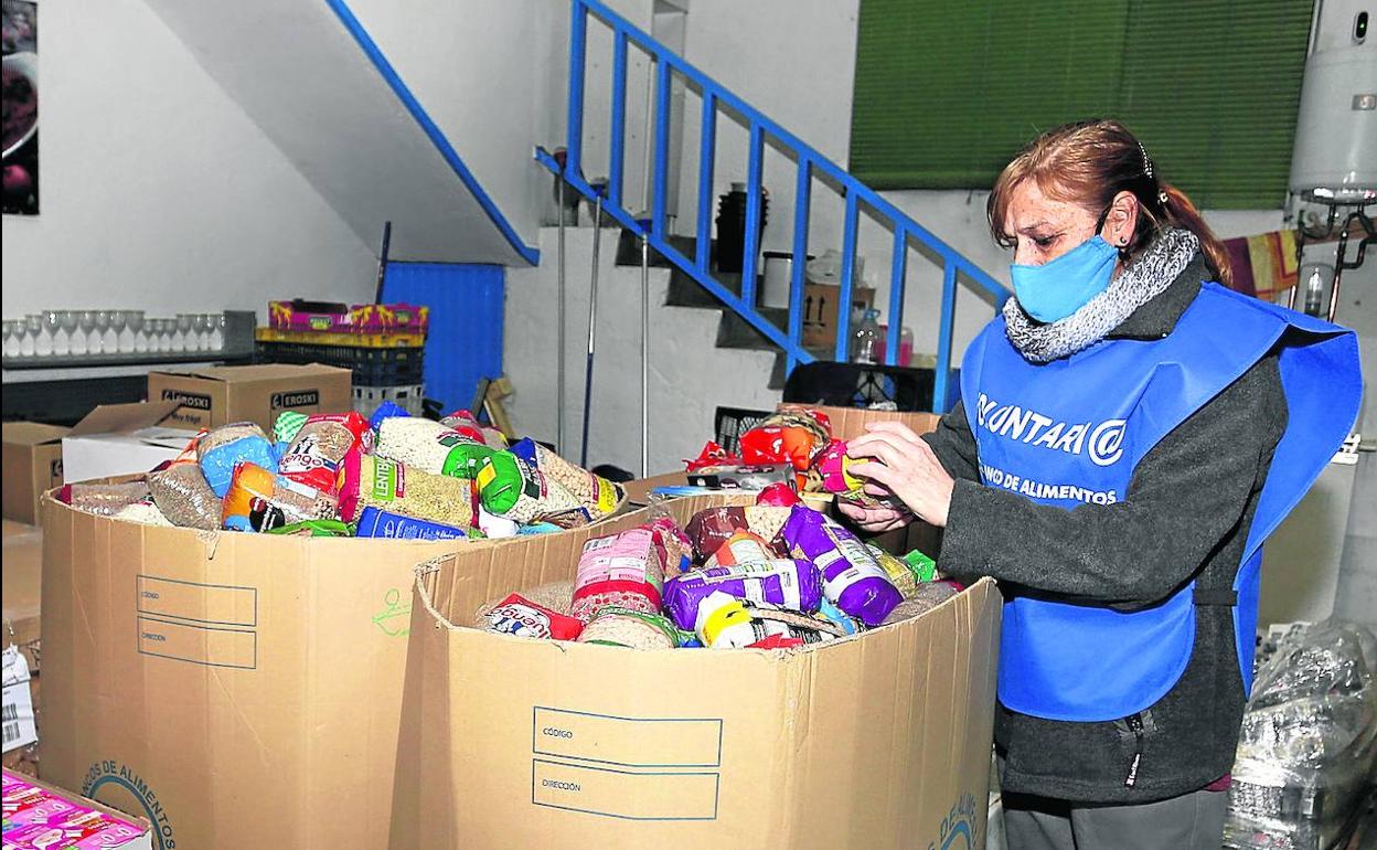 Una voluntaria organiza las cajas de alimentos recibidos en la campaña de Navidad.