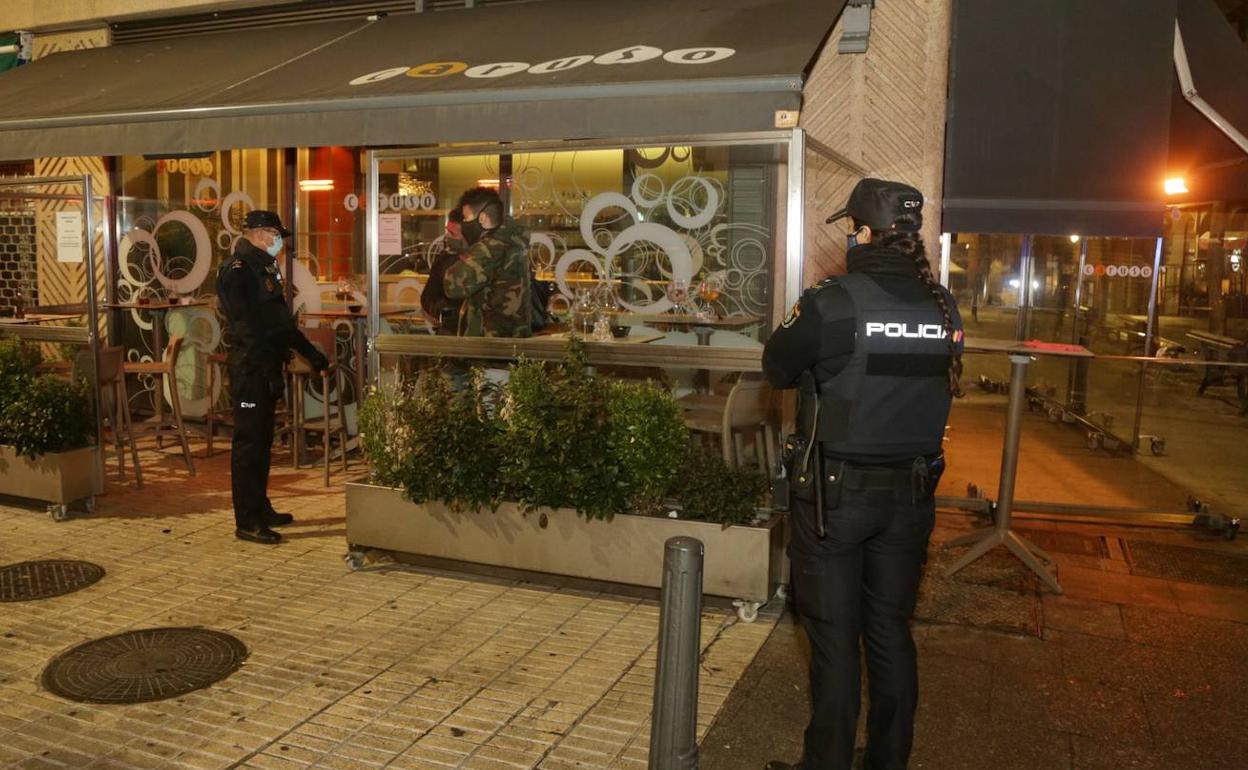 Agentes de la Policía Nacional instan a dos jóvenes a que abandonen una terraza en la plaza de Coca. 