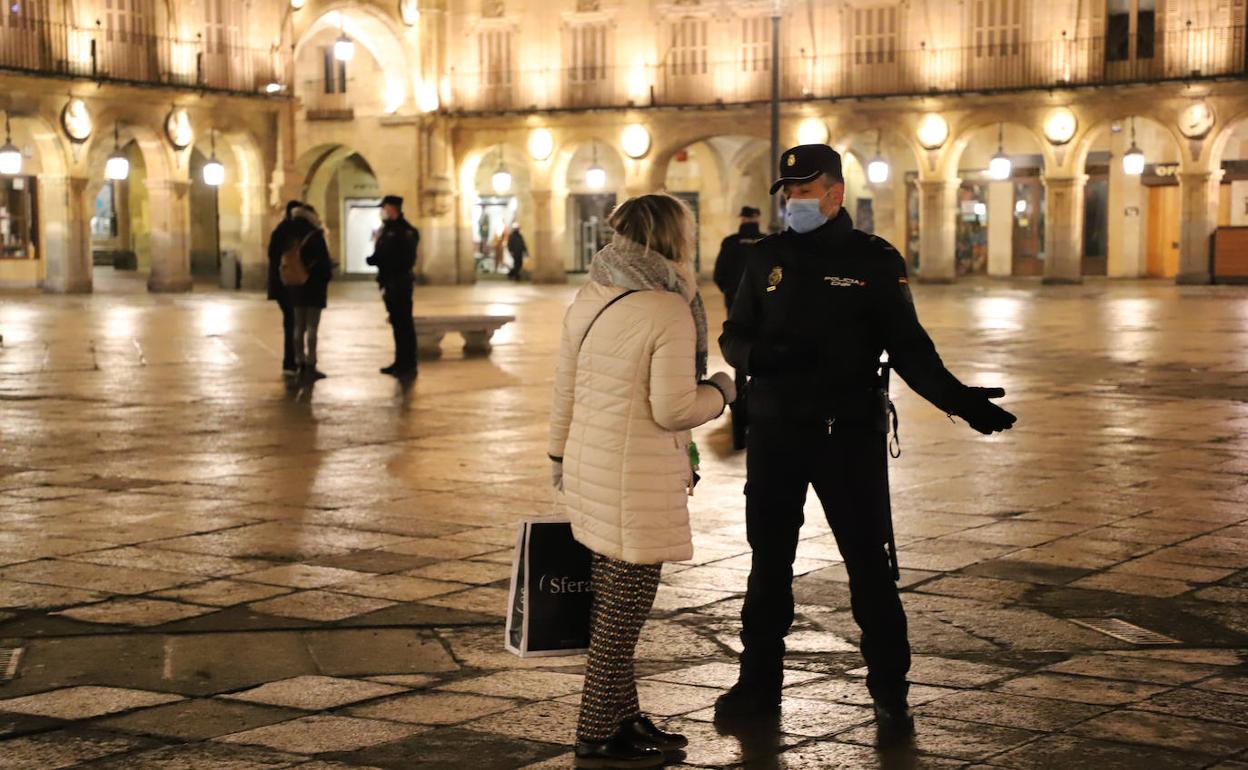 Un agente de la Policía Nacional habla con una vecina de Salamanca una vez impuesto el nuevo toque de queda.