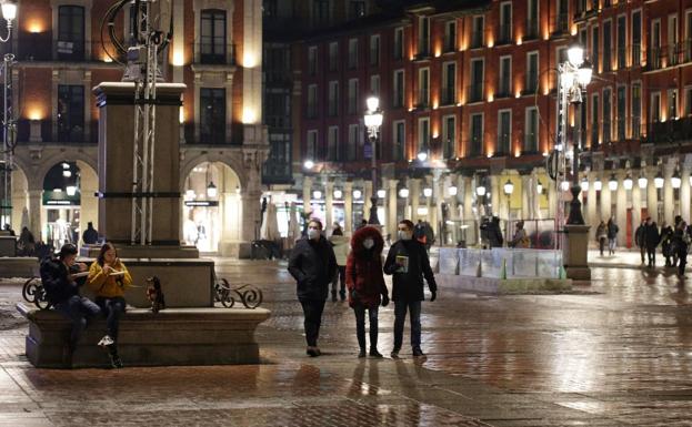 Imagen principal - Varias personas, en la Plaza Mayor minutos antes de la entrada en vigor del toque de queda; la policía patrullando junto a La Criolla después de las 20:00 y recogida de una terraza en la Plaza Mayor.