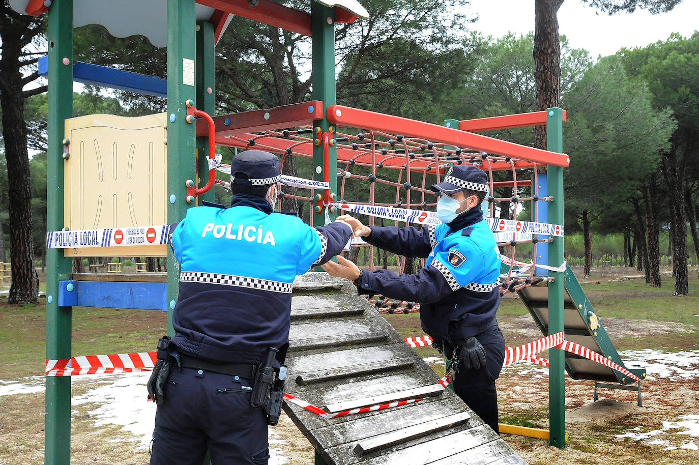 Dos agentes de la Policía Local precintan una zona infantil. 