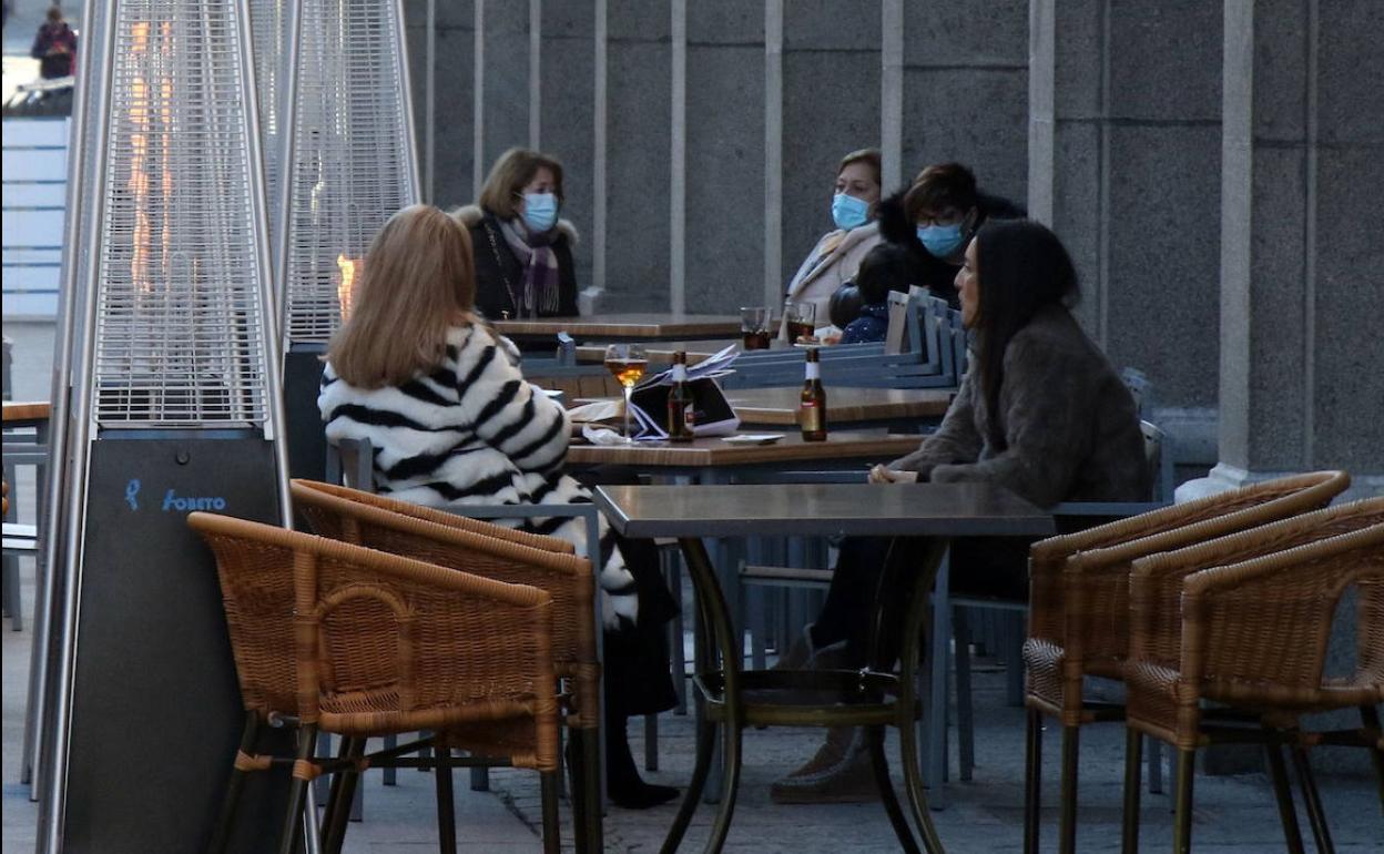 Varias personas tomando algo en una terraza de Segovia. 