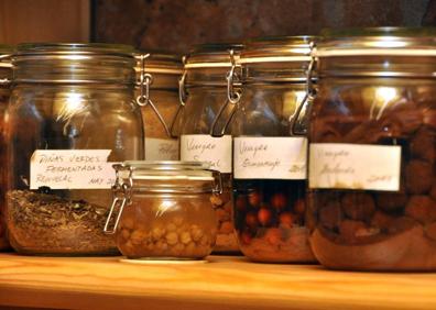 Imagen secundaria 1 - Arriba, Miguel Ángel de la Cruz huele un gran tarro con jalea de piña verde, preparada por él. Abajo, varios tarros con vinagres y otros productos, y el chef en la cocina bilbaína. 