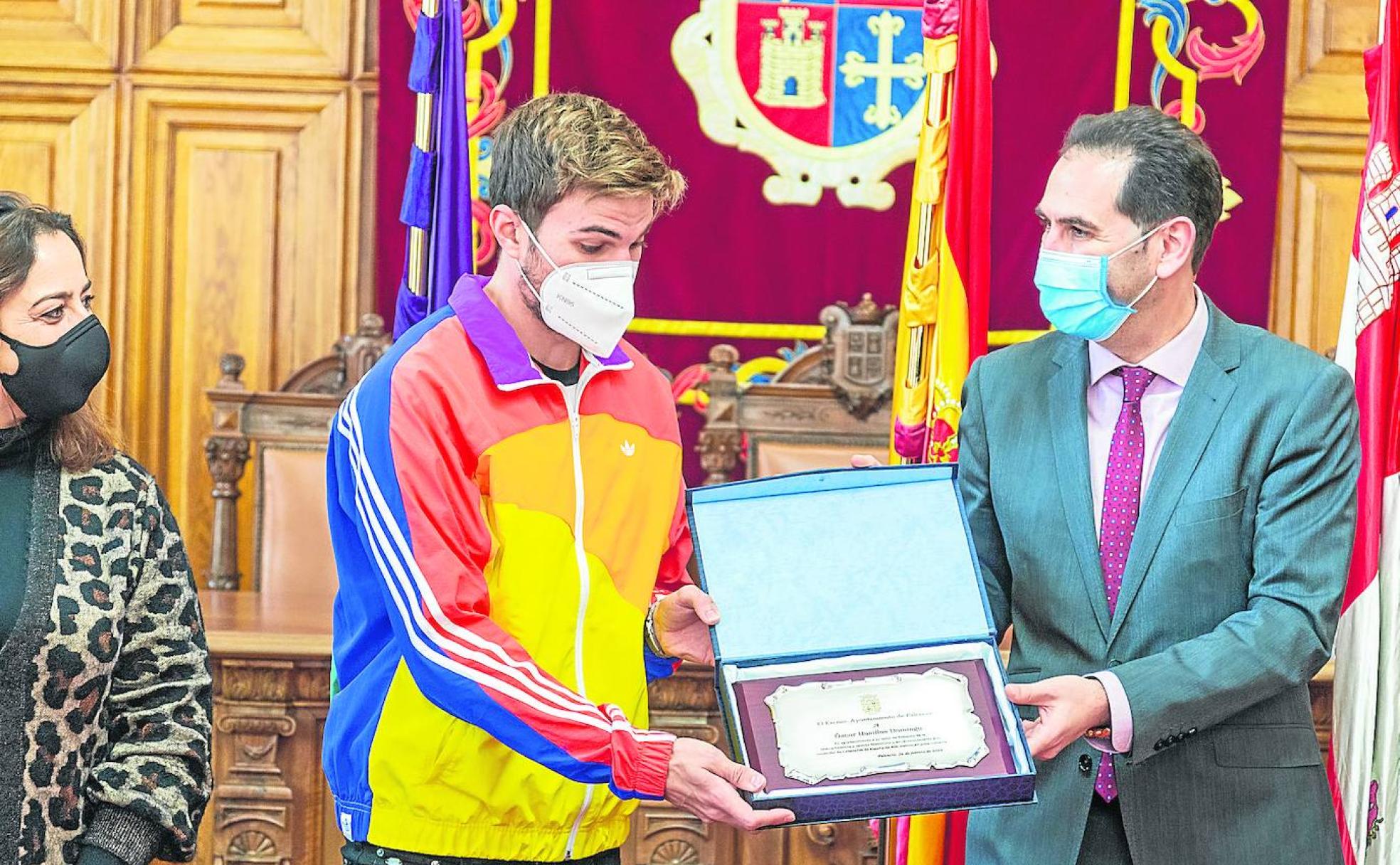 Con la portavoz socialista Miriam Andrés a la izquierda, Husillos y el alcalde, Mario Simón, muestran la placa concedida por el Ayuntamiento de Palencia por su reciente medalla de campeón de España. 