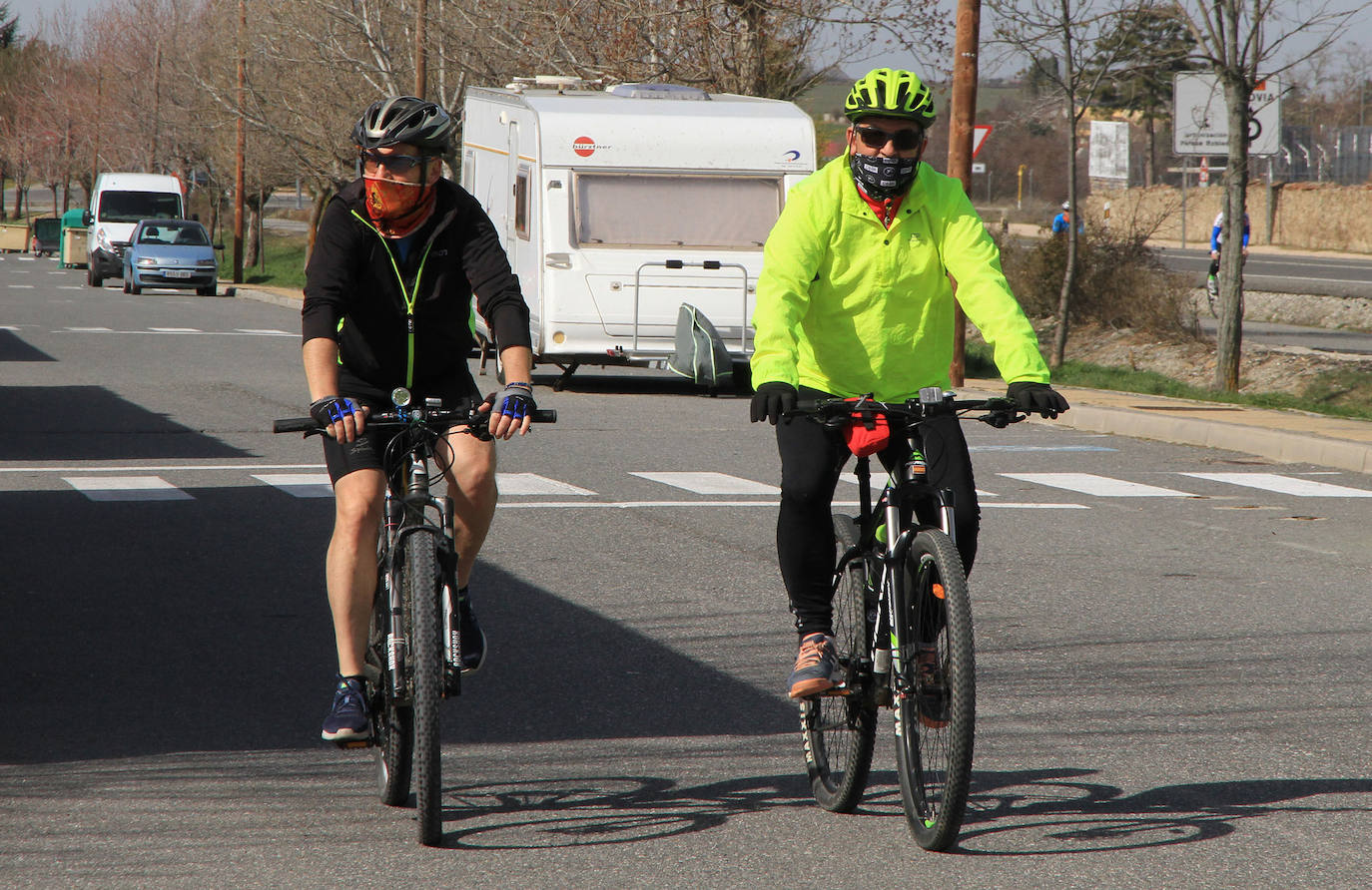 Dos ciclistas circulan por una calle paralela a la carretera de La Granja.