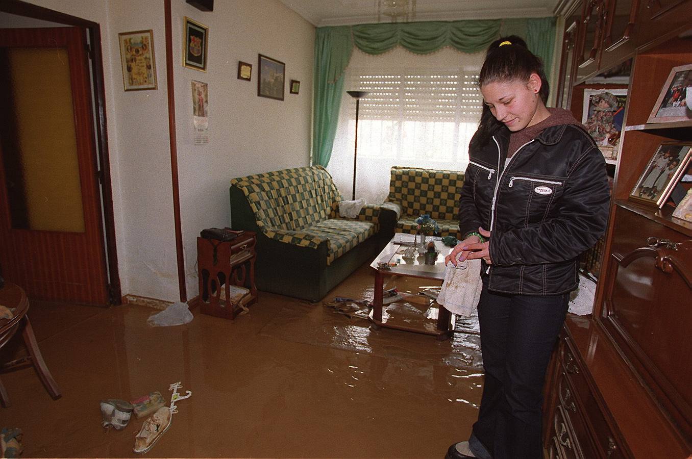 Una joven contempla el salón de su casa en la calle Ecuador del barrio Arturo Eyries, anegado por el agua y el barro.