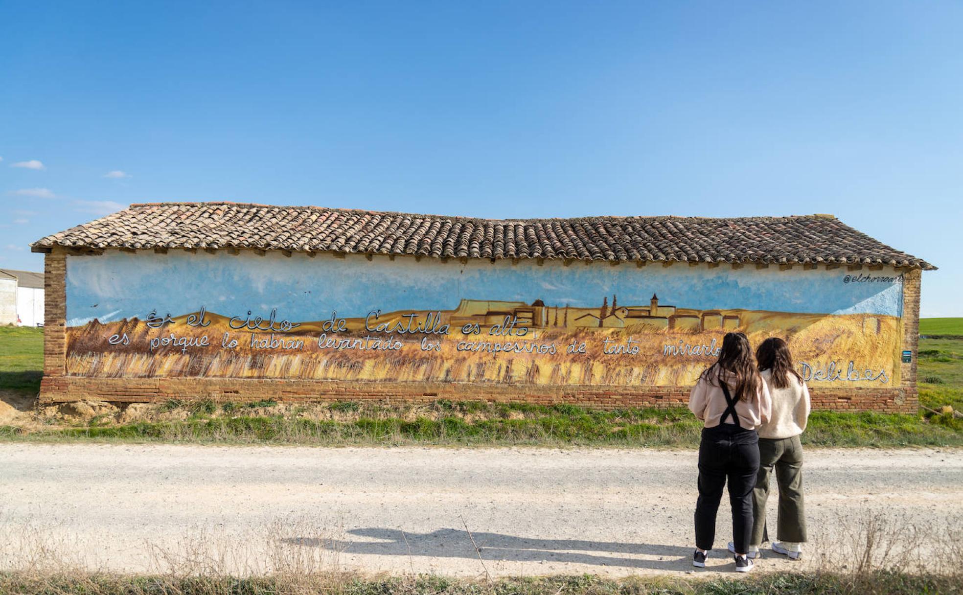 Laura y Andrea Antón contemplan un mural con la frase de Delibes. 