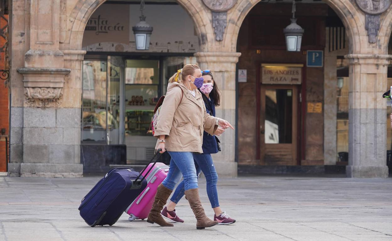 Una pareja de turistas pasea por la Plaza Mayor.