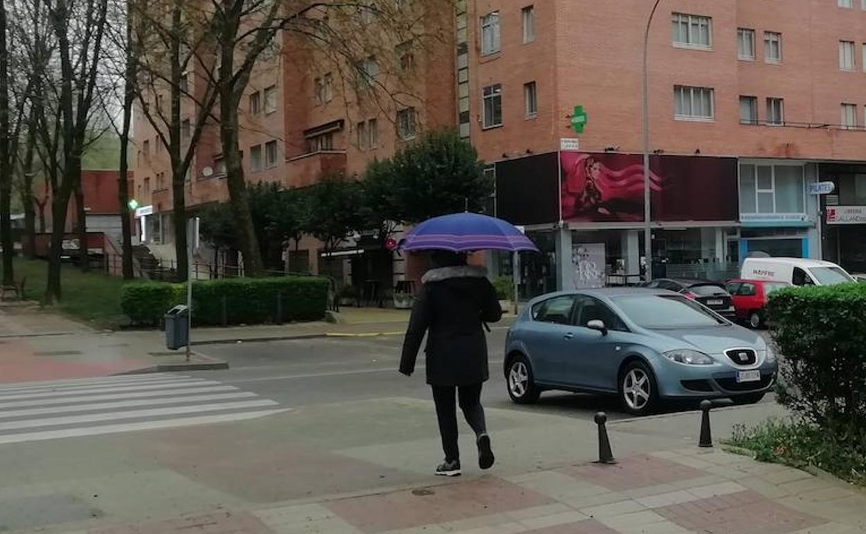 Una mujer se protege de la lluvia esta mañana en Parquesol.