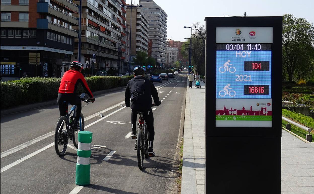 Dos ciclistas pasan junto al medidor del carril bici del paseo de Isabel la Católica.