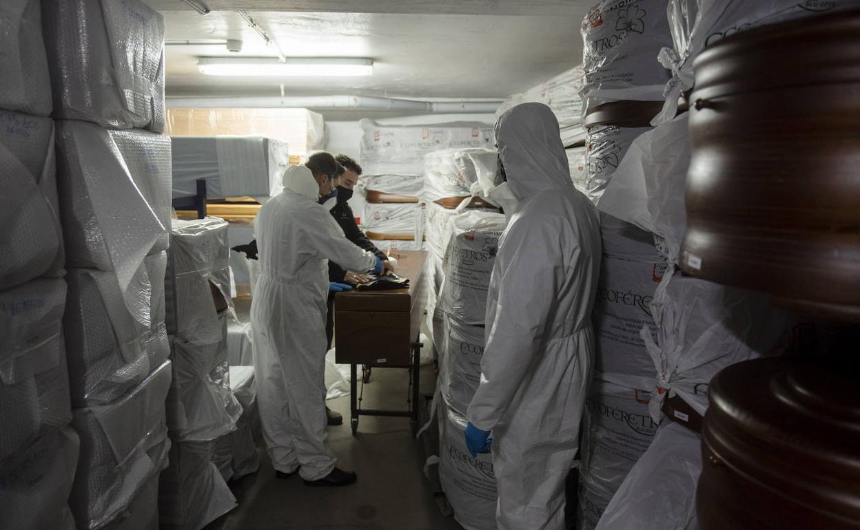 Trabajadores de servicios funerarios de Segovia preparan un féretro para su traslado durante la pandemia del coronavirus. 