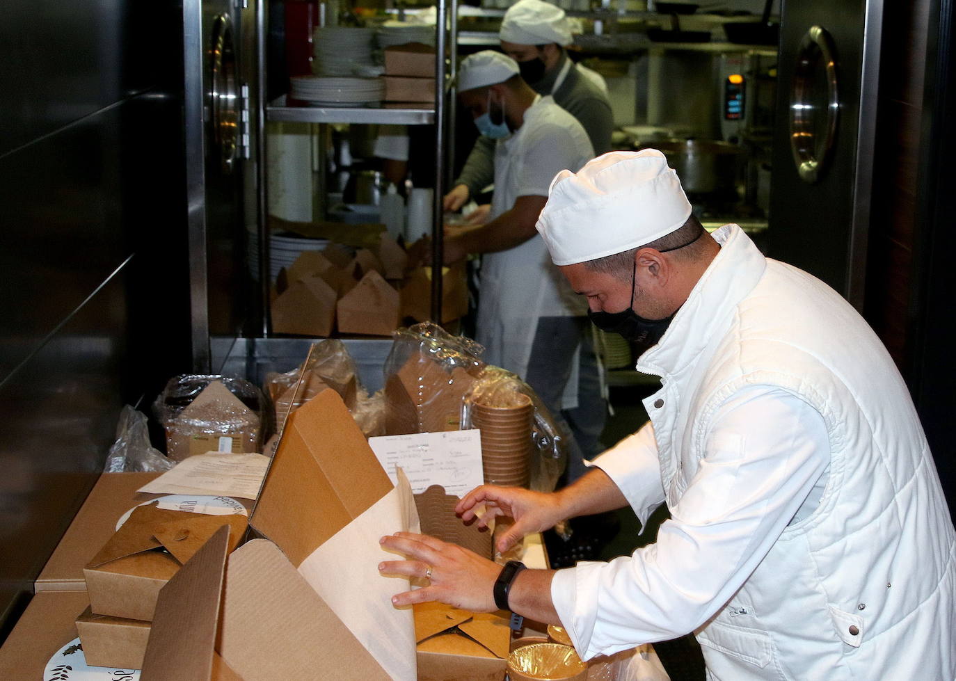 Cocineros preparan unas cajas de comida a domicilio. 