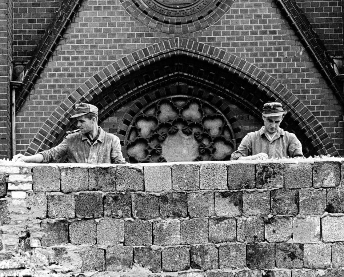 Trabajadores de Alemania del Este siembran de cristales rotos la parte de arriba del Muro.