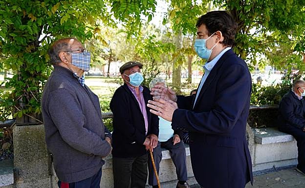 Imagen principal - Mañueco conversa con varias personas mayores tras haberse vacunado en el Multiusos 