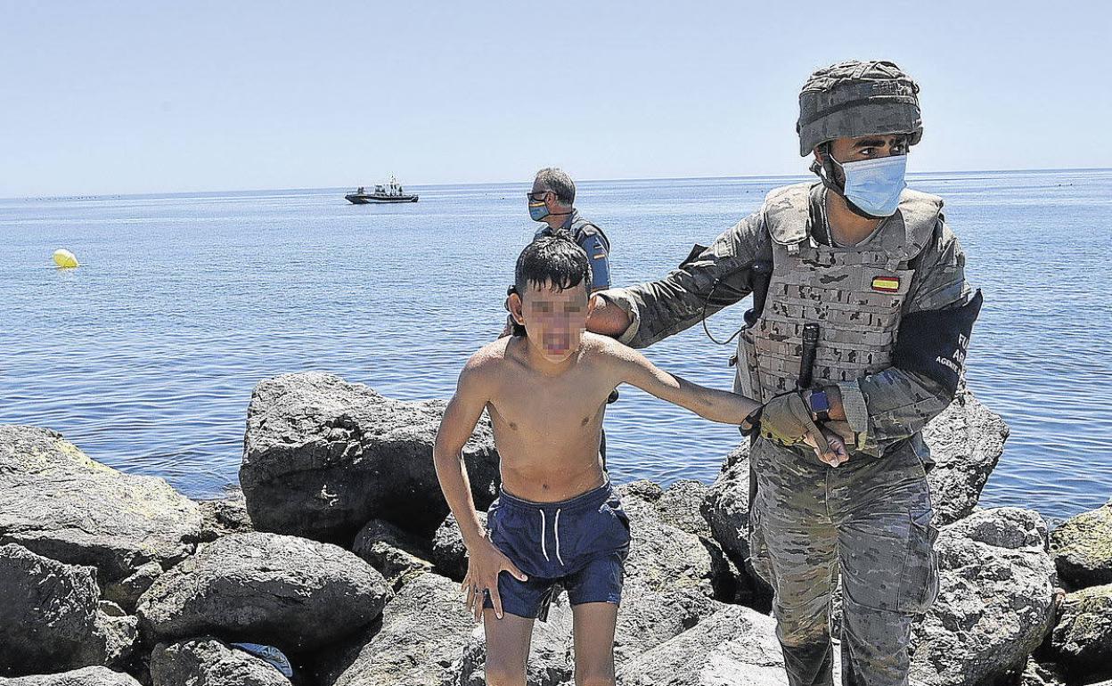 Un militar español ayuda a un menor marroquí a su llegada a nado a Ceuta. 