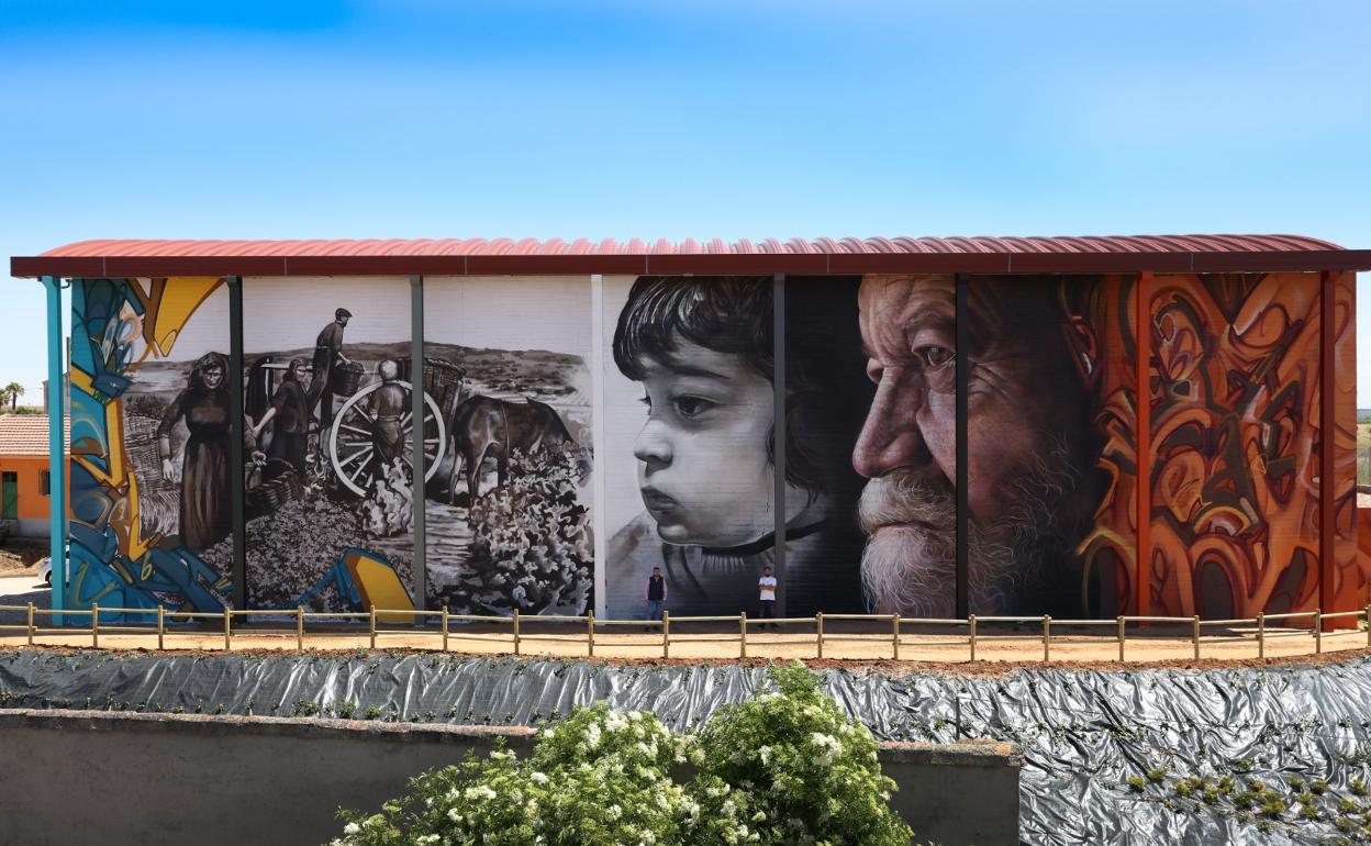 El alcalde, Santiago Castañeda, y el autor de los murales, Daniel Martín, delante de la pintura para que se vean las dimensiones de la obra realizada en 400 metros cuadrados. 