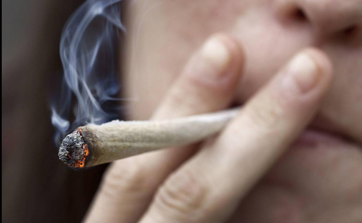 Un joven fuma un porro.