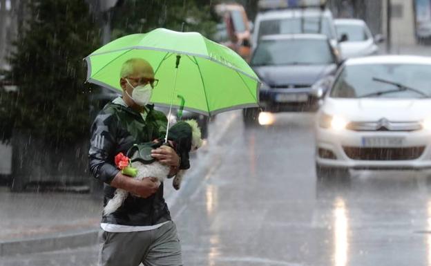 Un vallisoletano protege de la lluvia a su perro. 