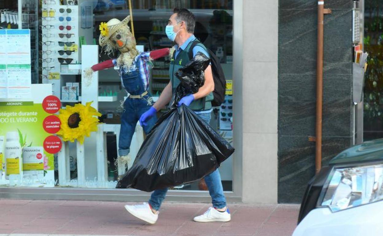 Un agente de la Guardia Civil se lleva una bolsa intervenida en el registro de la casa. 