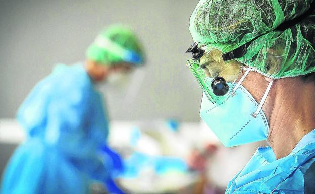 Dos sanitarios trabajando en un hospital con trajes de protección. 