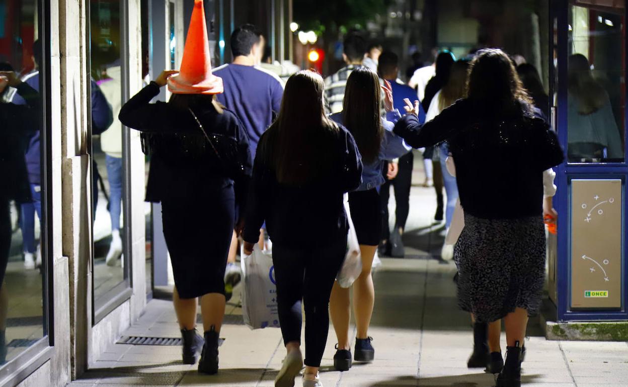 Un grupo de jóvenes, cargados con bebidas, se dirigen hacia un botellón. 