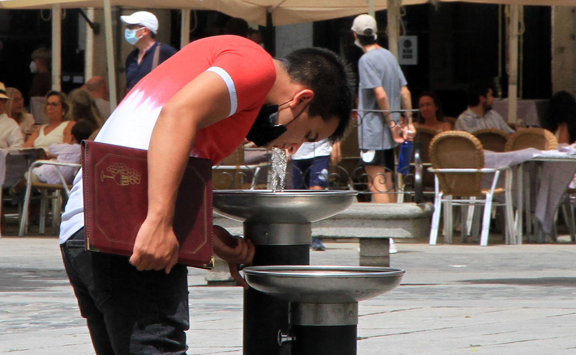 Un chico bebe agua de una fuente para refrescarse del calor de este domingo en Segovia. 