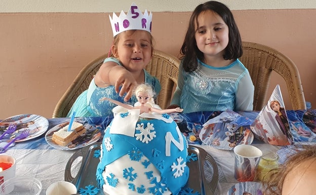 Nora y su amiga Julia, disfrazadas de Frozen, contemplan la tarta de su personaje favorito