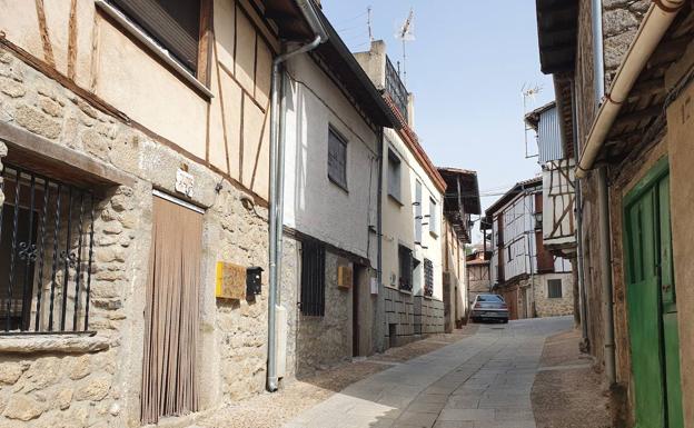 Imagen principal - Una de las calles en las que se pueden ver varias tapas de contadores, detalle de una de ellas, y estandarte en una de las fachadas.