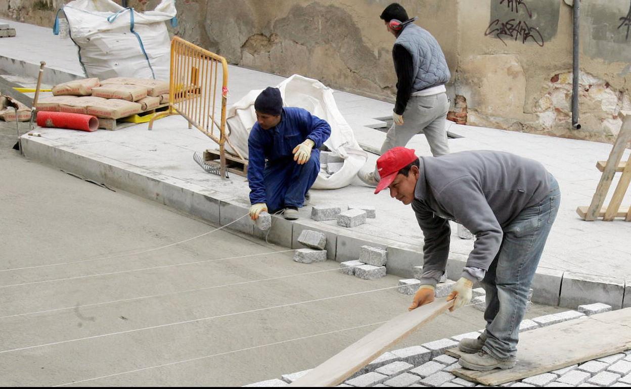 Obreros trabajan en el adoquinado de una calle.