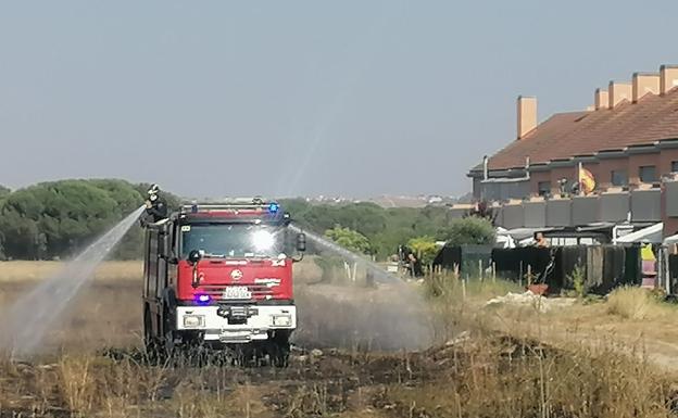 Uno de los camiones de Bomberos de la Diputación enfría la zona quemada, a escasos metros de algunas viviendas de la urbanización de Aldeamayor Golf, en Valladolid.