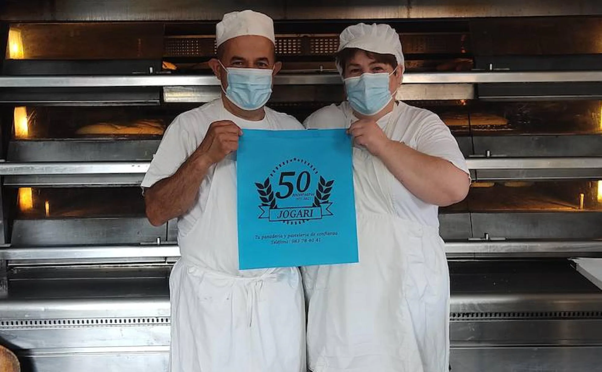 Moisés García y Elena Díaz muestran una de las bolsas que conmemoran los cincuenta años de vida de la panadería-pastelería Jogari de San Román de Hornija