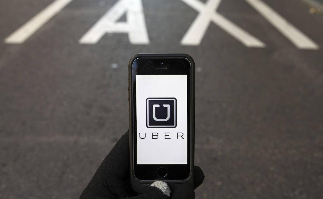 Un smartphone conectado a la aplicación Uber sobre el símbolo de taxi. 