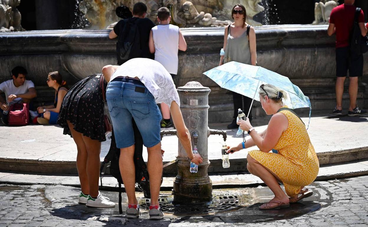 Los turistas recogen agua en una fuente de Roma.