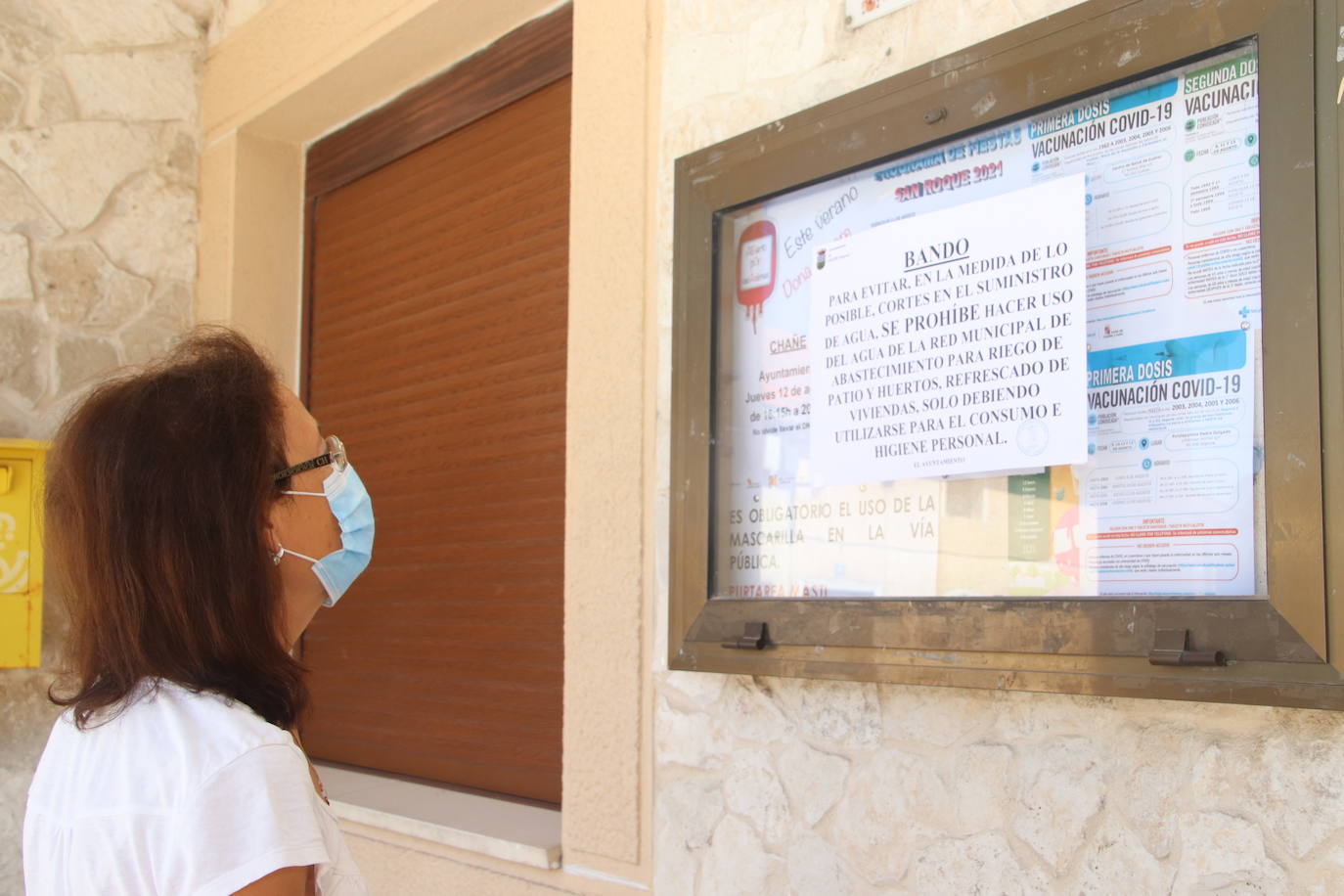 Una vecina lee el bando en el tablón de anuncios del Ayuntamiento de Chañe, ayer.
