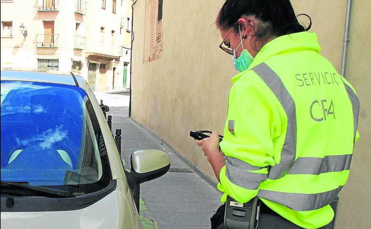 Una empleada de la ORA comprueba un vehículo estacionado. 