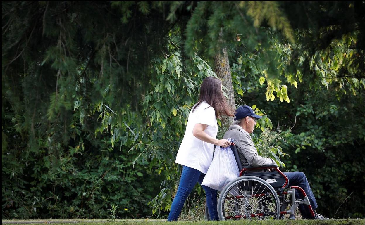 Una mujer pasea con un hombre en silla de ruedas.
