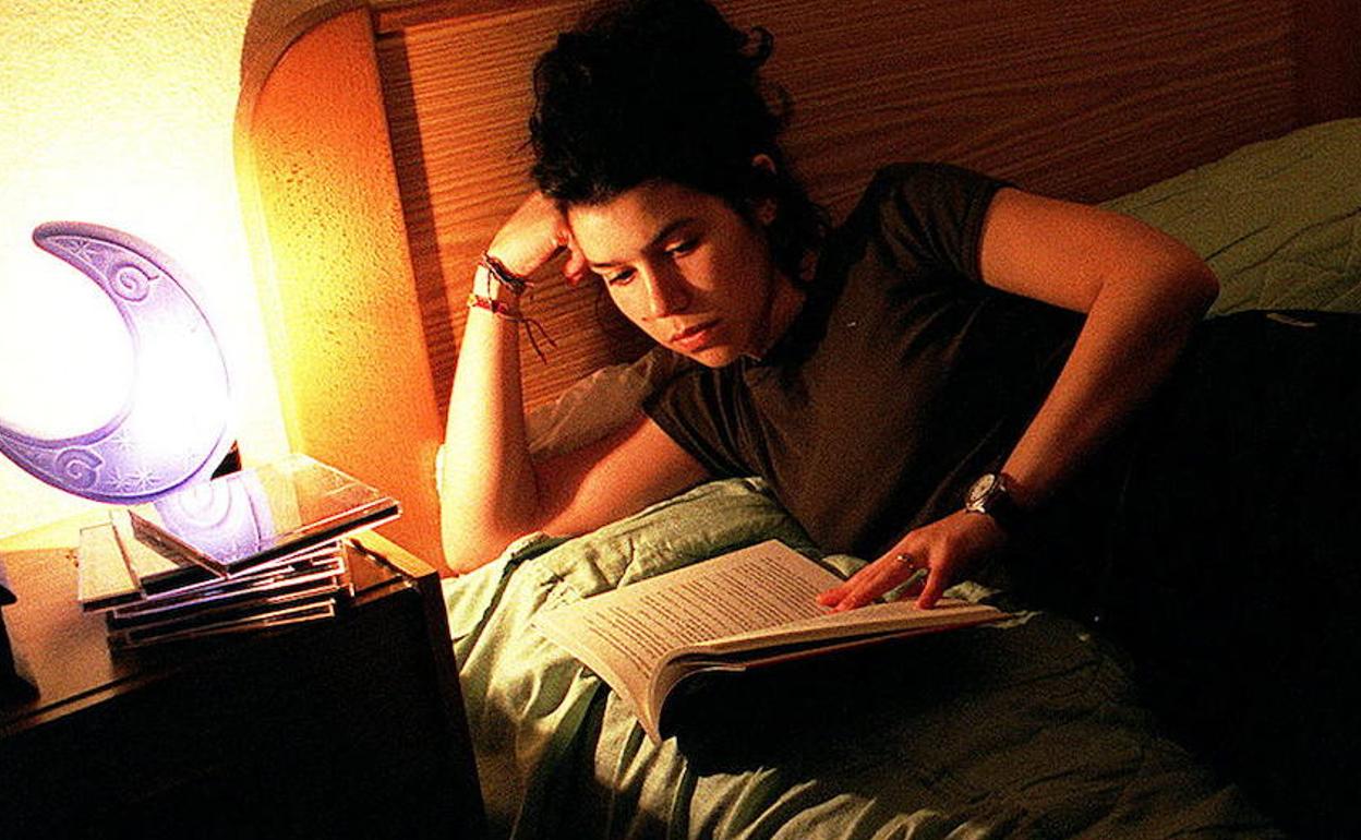 Una chica lee un libro tumbada en la cama