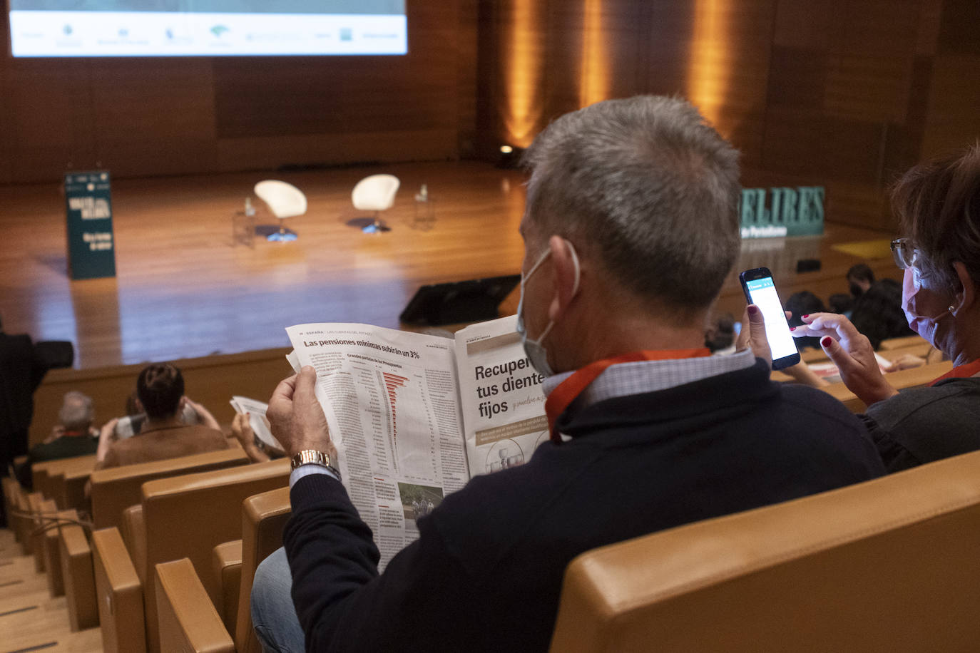 Los asistentes al congreso leen el periódico mientras esperan a que arranquen las ponencias. 